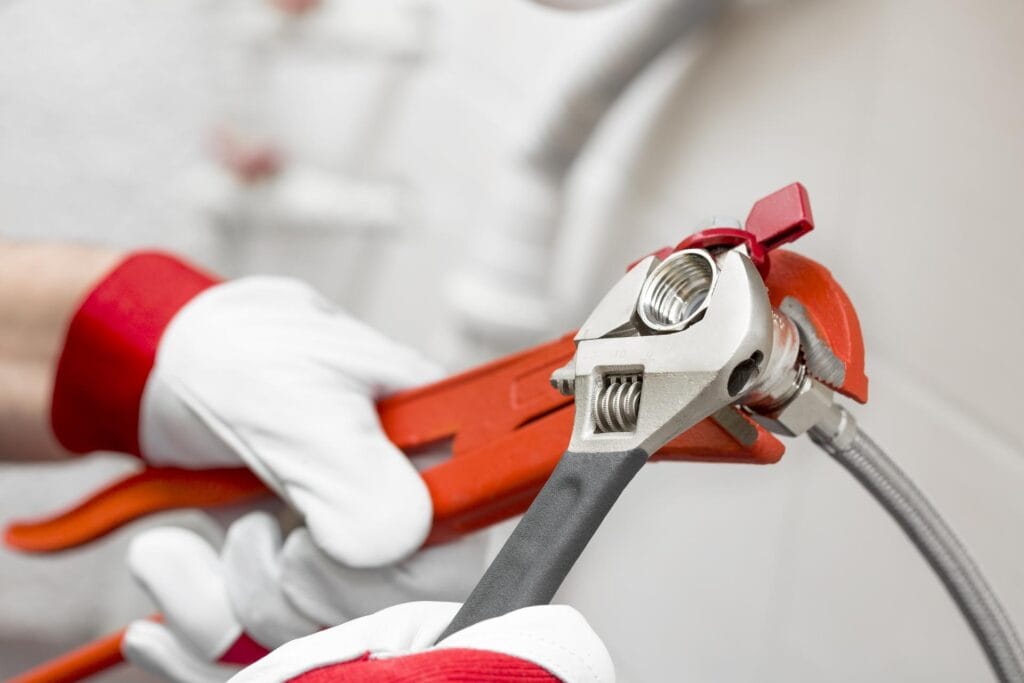 Plumber holding pipe wrenches for an emergency repair in Wildomar