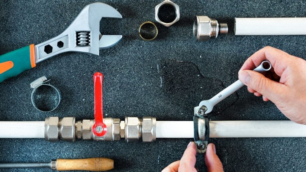 Plumber repairing a pipe valve with an adjustable wrench in Wildomar