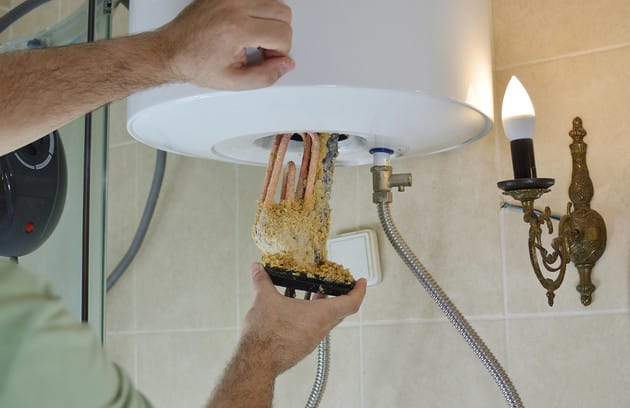 Technician removing mineral buildup from a water heater in Wildomar