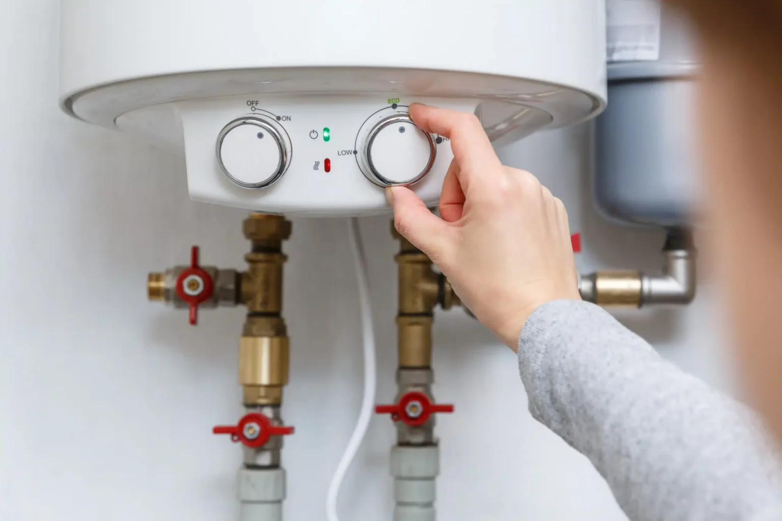 Homeowner adjusting the temperature controls on a water heater in Wildomar